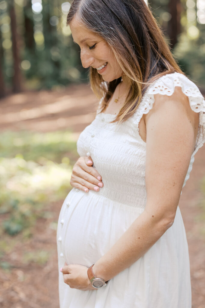 close up shot of expecting mother in white dress in the Oakland redwoods