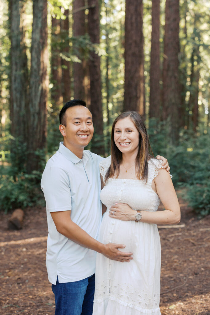expecting couple smile in the Oakland redwoods during their Bay Area maternity photography session