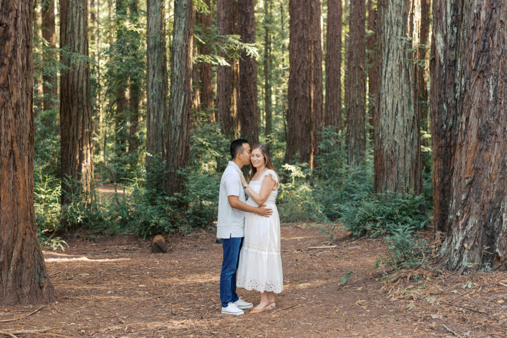 expecting couple stands in the redwoods during their Oakland maternity photography session
