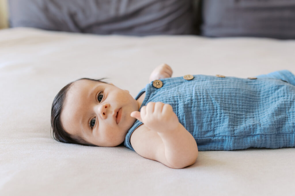 2 month old newborn boy lays on white bed during Redwood City newborn session