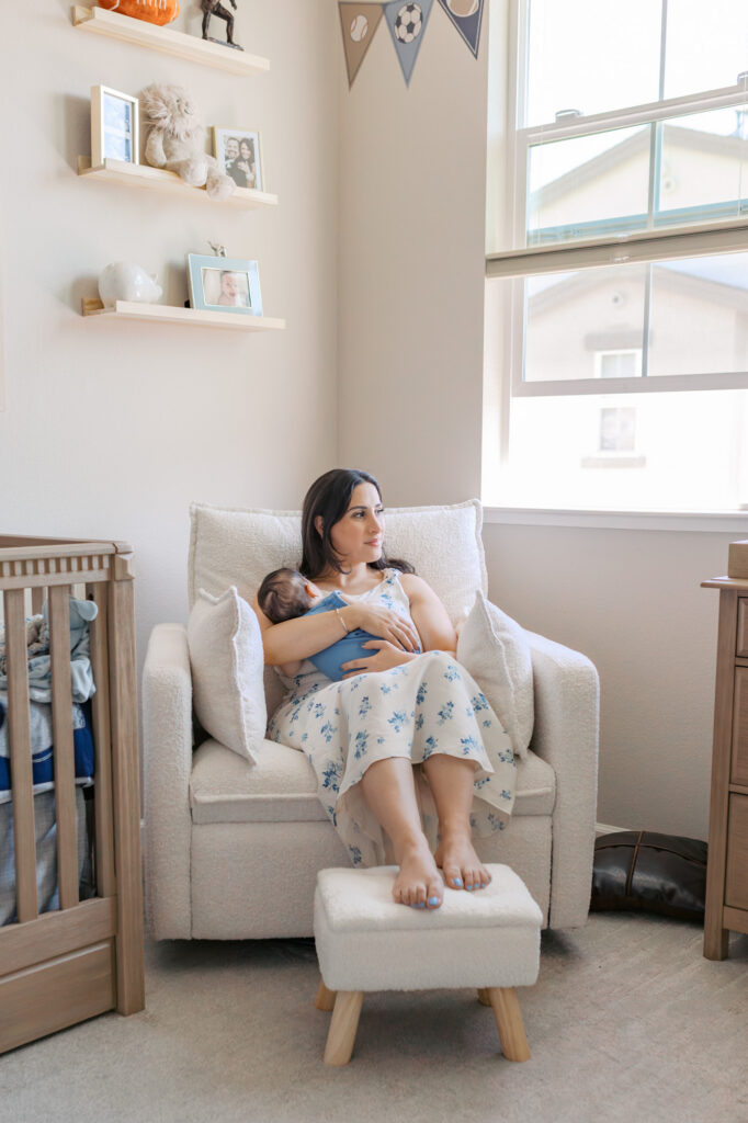 mom relaxes in football themed nursery, rocking her sleeping 2 month old during Redwood City newborn session