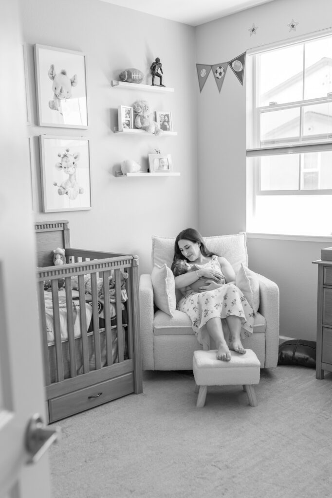 new mom rocks 2 month old newborn while in his football themed nursery in Redwood City