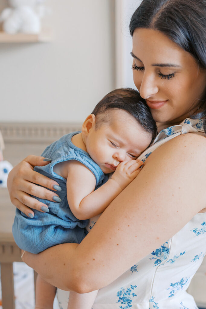 Redwood City newborn session with baby at 2 months old. Mom holds sleeping baby in her arms in his football themed nursery.