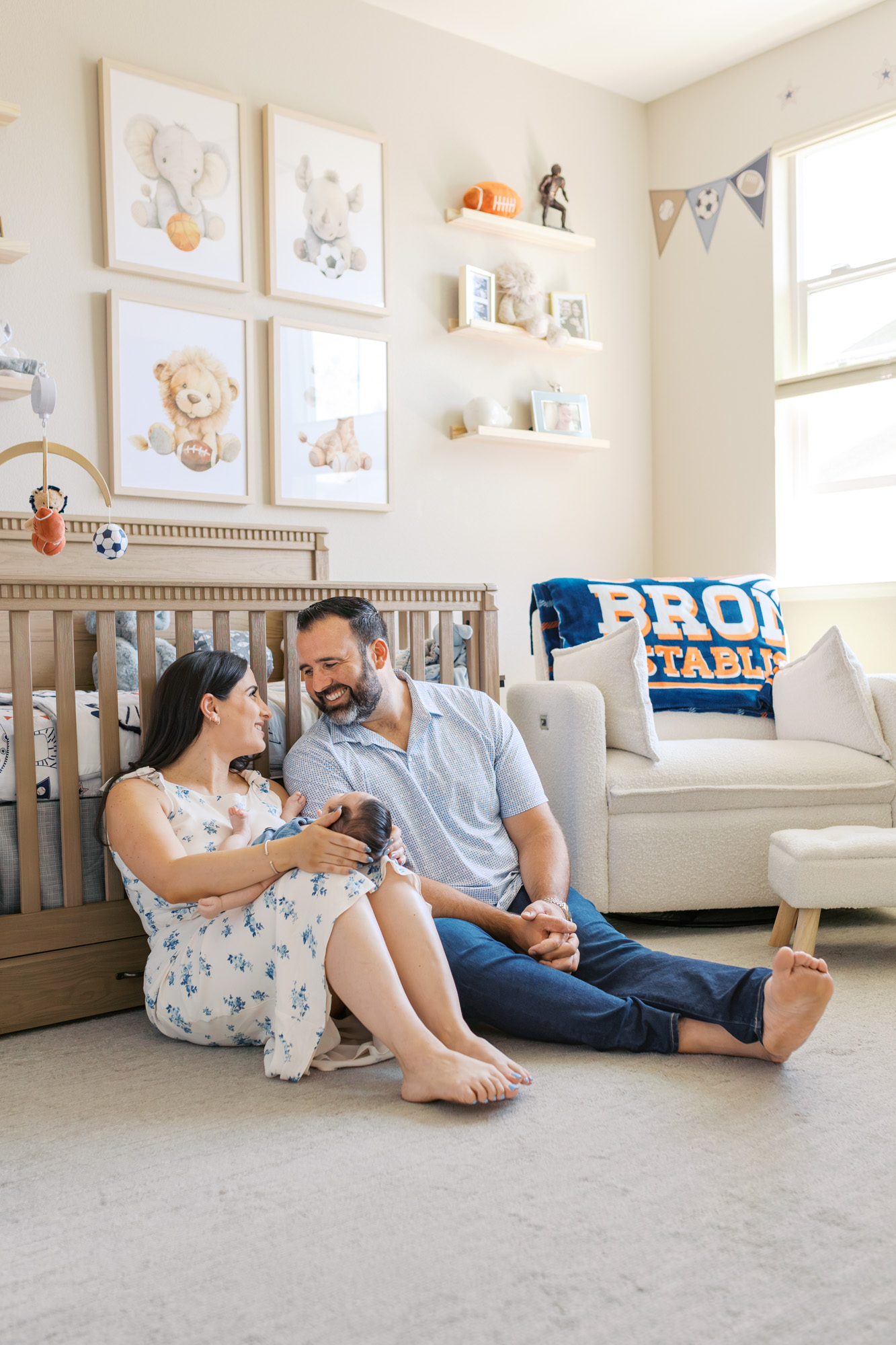 new parents sit in football themed nursery with their 2 month old baby boy during Redwood City newborn session
