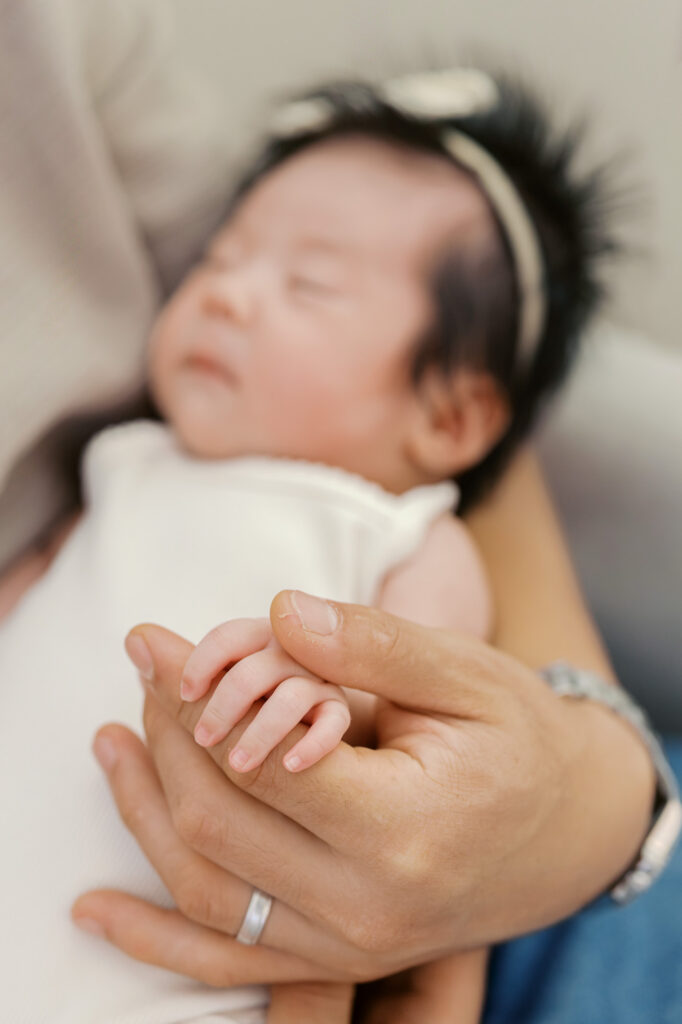 detail shot of one month old's fingers in dad's hands