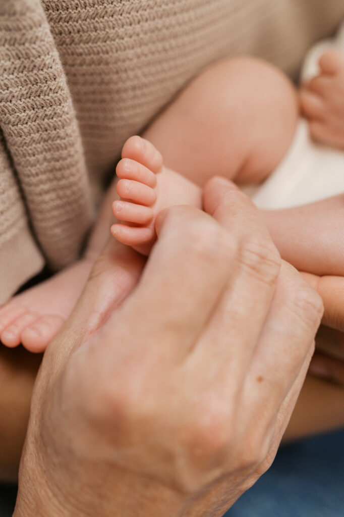detail shot of grandfather holding newborn baby's foot