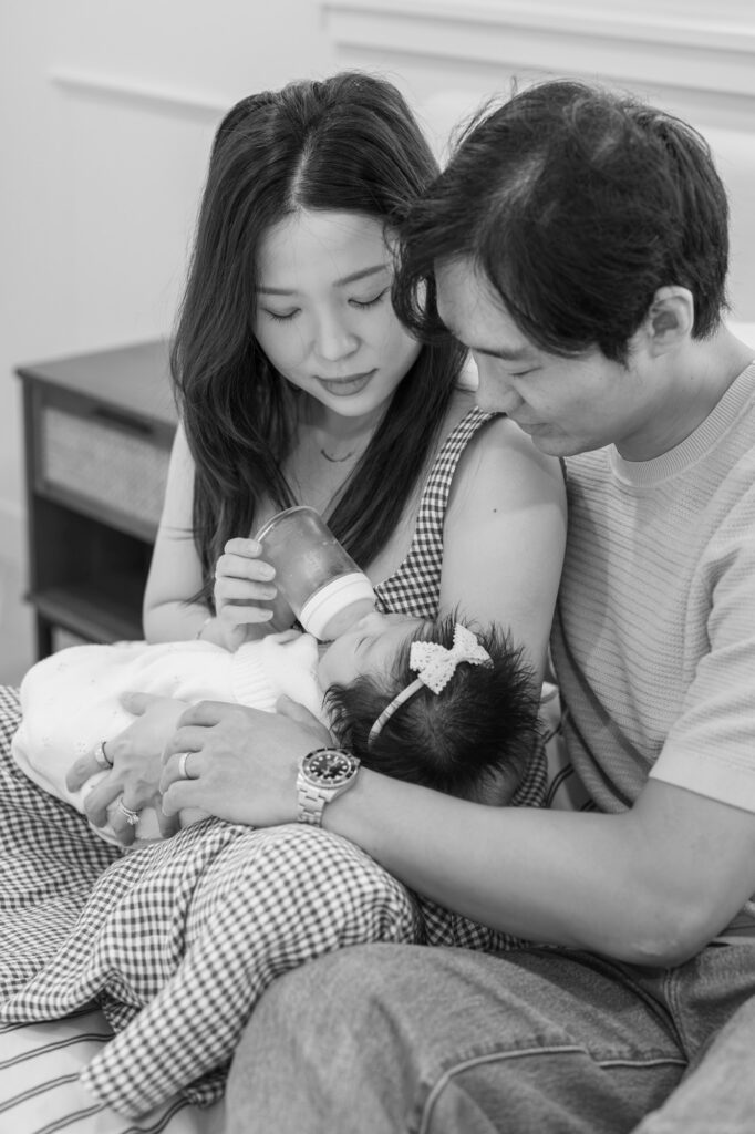 parents feed newborn baby a bottle during their Santa Clara newborn photography session, black and white image