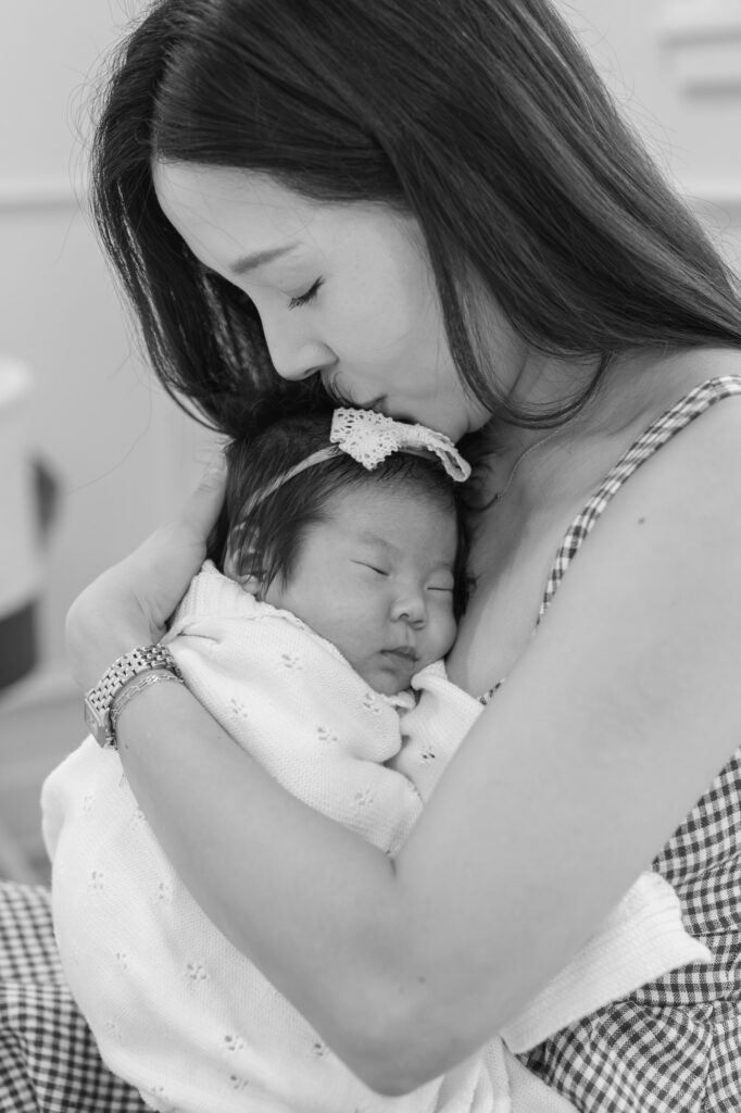new mom kisses sleeping newborn, black and white image