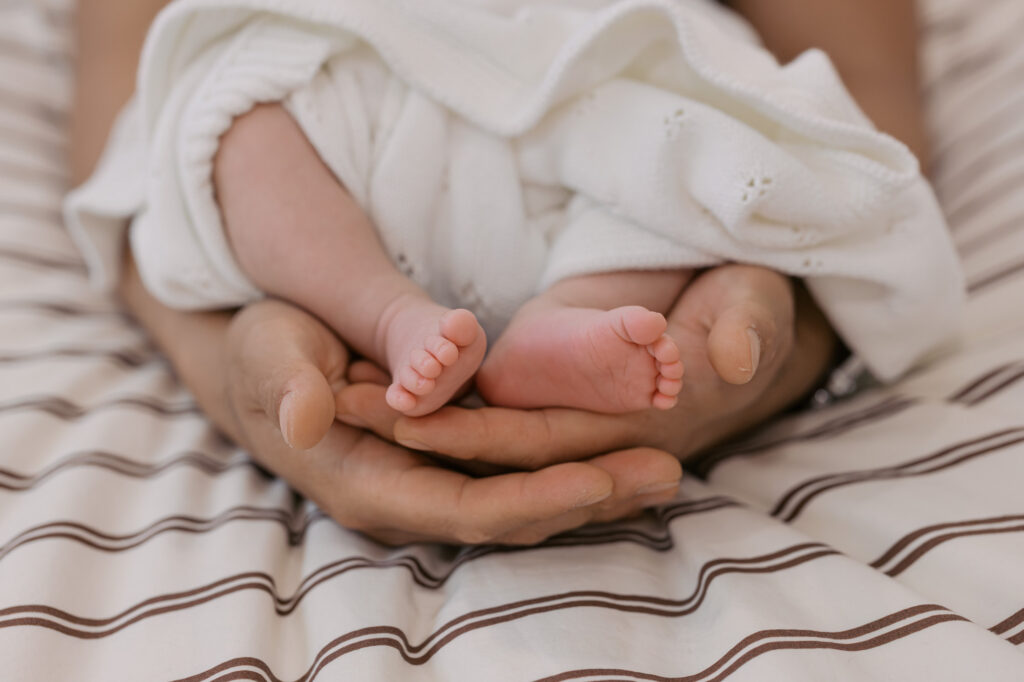 parent holds newborn baby's feet for a detail photo during newborn photography session