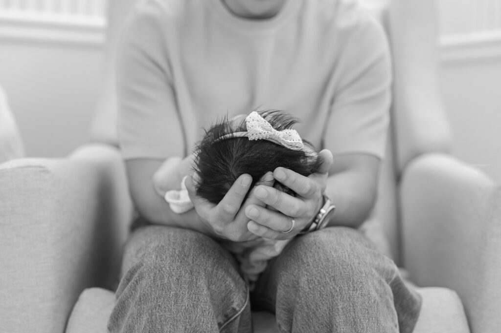black and white image of dad holding baby's tiny head in his hands during Santa Clara newborn photography session