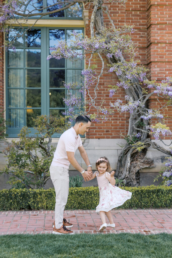 Dad and daughter dance next to the Filoli wisteria during their Bay Area family photography session
