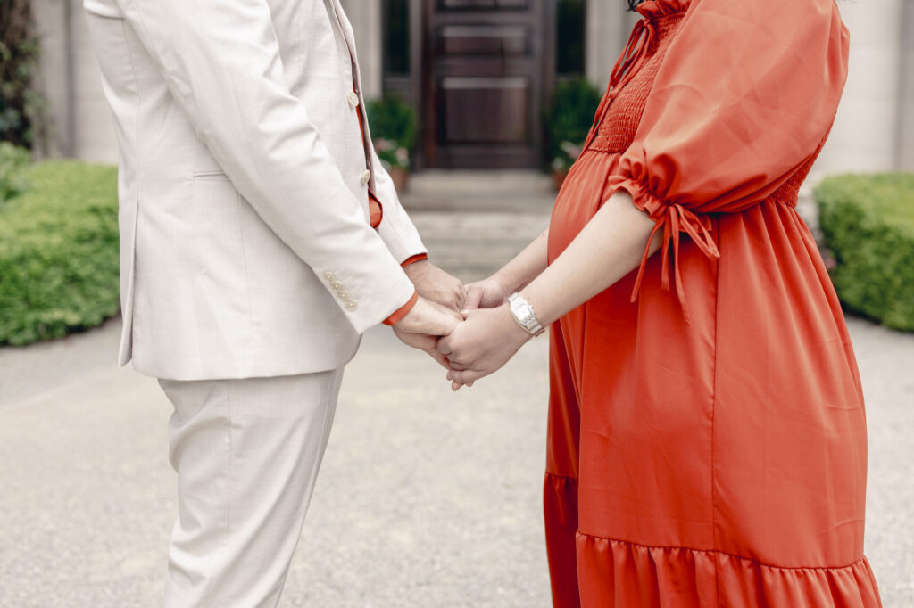expecting couple hold hands in front of the Filoli estate house
